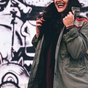 woman wearing olive green jacket in front of graffiti