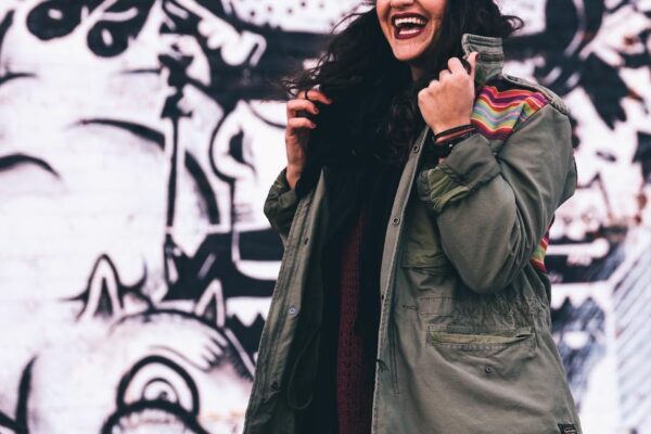woman wearing olive green jacket in front of graffiti